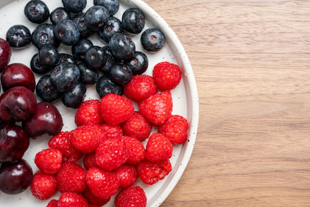 High resolution fruit photo of mixed fruits including cherries, raspberries and blueberries arranged...