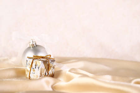 a small gift and a Christmas tree ball on a beige golden backgroundの写真素材