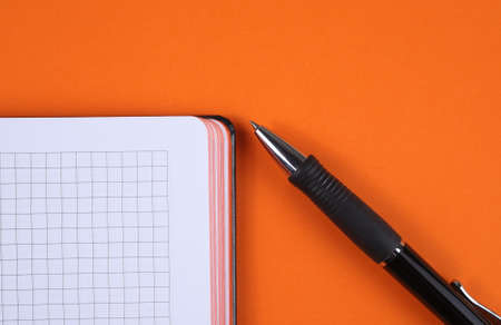 note book and black pen on an orange background close-up. Notesの写真素材
