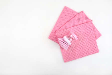 Three pink cleaning clothes for cleaning and a pink brush for washing on a white background.