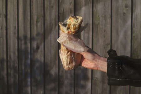 shawarma in hand close-up on wooden background