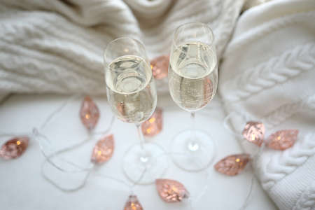 Two glasses of champagne decorated with a garland on a white backgorund.の写真素材