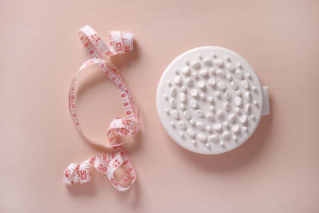 Massage brush and measuring tape on a pink background. weight loss concept