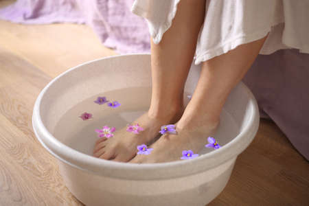 female feet in spa bowl with flowersの写真素材