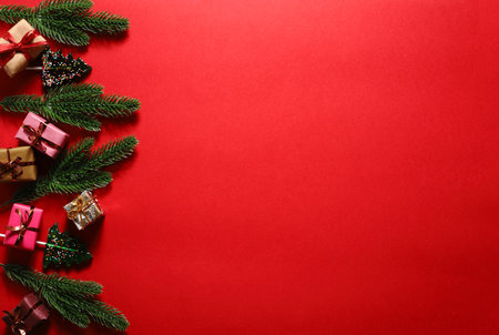 Red Christmas background with fir branches gifts and lollipops.の写真素材