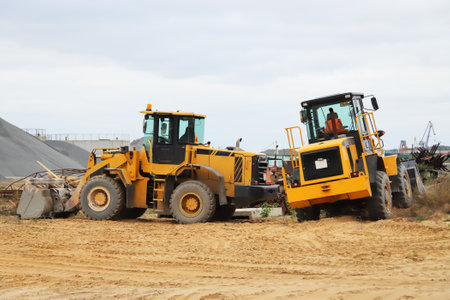 Two yellow heavy wheeled bulldozers in the construction sand areaの写真素材