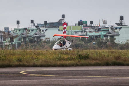 Pokhara, Nepal- December 4 2019: An ultralight aircraft taking off from a runway with a pilot and passenger.のeditorial素材