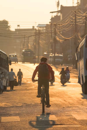 Morning rush in the streets of Pokhara, Nepal. Young man taking his bicycle to the streets of Nepal in early morning; on the way to his job.の写真素材