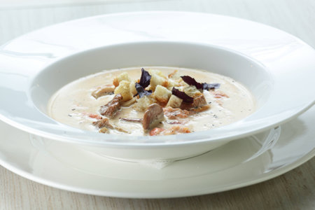 Hot soup in the white dish on wooden tableの写真素材