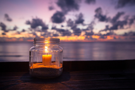 Candle lamp on wooden table with sea and sunset background, romantic dinner in the restaurant. Indonesia Baliの写真素材