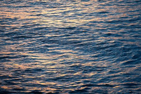 Ocean waves and the water surface at sunset with the reflection of the sunの写真素材