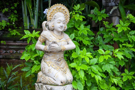 Girl statue in white stone in Balinese style on the background of greenery, Indonesiaの写真素材