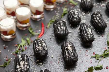 Catering cakes of black dough, eclairs and greens