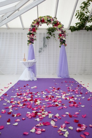 Empty wedding arch after the ceremony with flower petals on the pathの写真素材