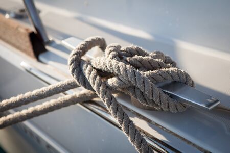 White mooring rope tied around steel anchor on boat or shipの写真素材