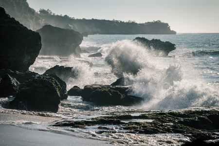 Ocean waves crashing onto the rocks in the sunsetの写真素材