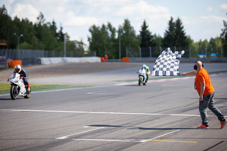 Man holding and waving the checkered flag at the finish of the raceの写真素材