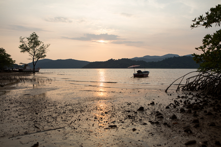 Boat at sea against mountains at sunset at low tide, tropical landscape of Thailandの写真素材