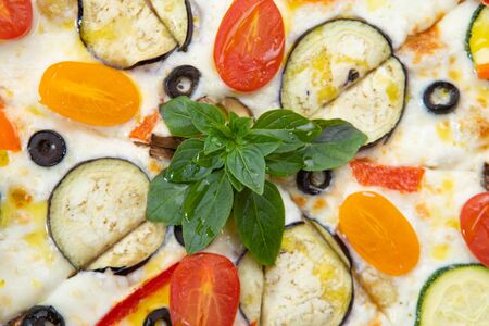 Pizza with vegetables close-up with various ingredients decorated with Basil, an assortment of traditional Italian fast foodsの写真素材