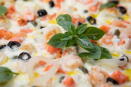 Close-up seafood pizza with various ingredients decorated with Basil, an assortment of traditional Italian fast foodsの写真素材