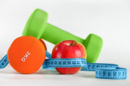 Dumbbells, apple and measuring tape on a white background. copy spaceの写真素材