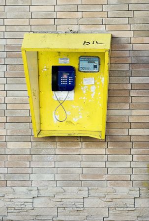 Yellow telephone box on biege brick wallの写真素材