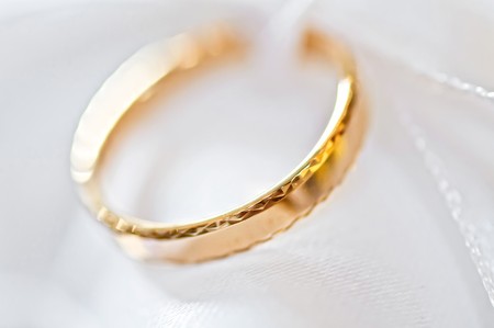 Classic gold wedding ring on white satiny fabricの写真素材