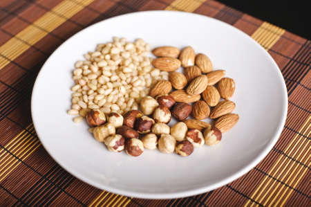 Mixed nuts on a white plate and brown table-napkinの写真素材