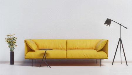 Yellow couch against a white wall with a lamp and flowersの写真素材