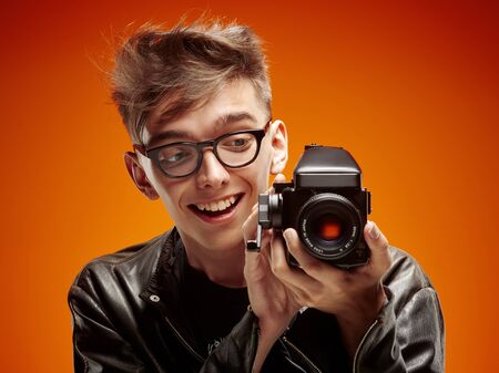 Emotional portrait of a teenager  with film camera on a red backgroundの写真素材