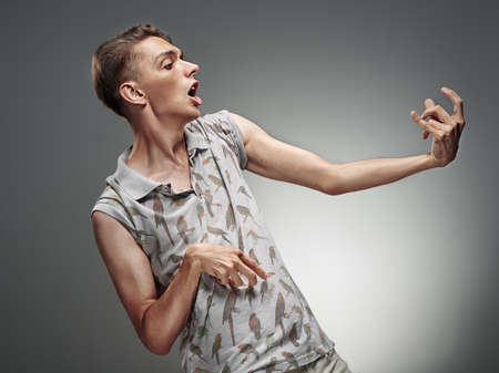 Emotional portrait of a teenager  playing on air guitar on a gray backgroundの写真素材