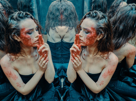Beautiful girl with a scar on her face in the blood in the looking glassの写真素材