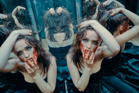 Beautiful girl with a scar on her face in the blood in the looking glassの写真素材