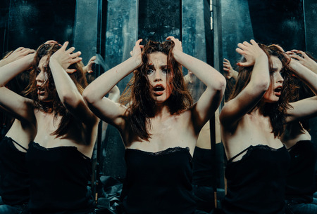 Beautiful girl with a scar on her face in the blood in the looking glassの写真素材