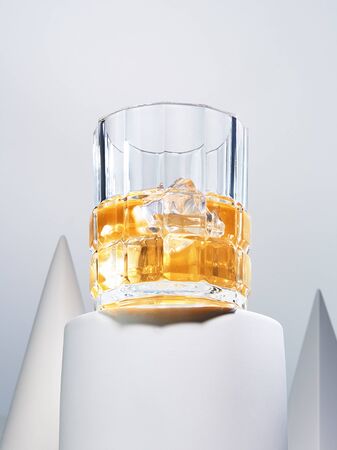 Bottom view of tasty alcohol beverage in glass. Refreshing drink with ice-cubes standing among geometric shapes. Gourmet and exquisite drinks conceptの写真素材