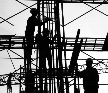 Construction Workers in Silhouette -- high up on the scaffoldingの写真素材