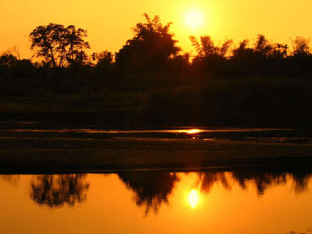 River at Evening Time -- with the sun and the trees reflecting in the waterの写真素材