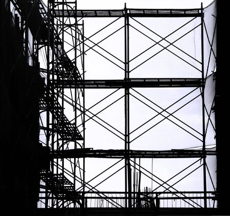 Construction Scaffolding-- seen as a silhouette with ladders and safety netsの写真素材