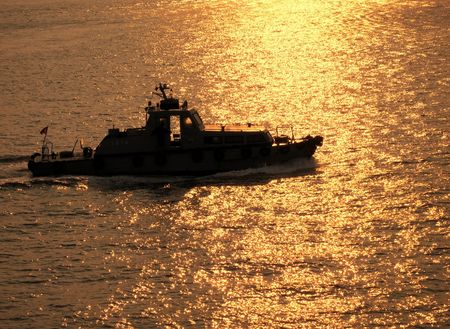 Coastguard Ship -- crossing the sea during sunset timeの写真素材