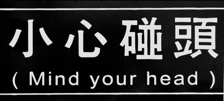Sign over Low Door -- it is written in both English and Chinese charactersの写真素材