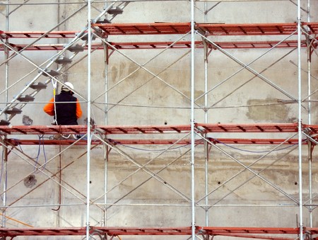 A construction worker is sitting on a metal scaffoldingの写真素材
