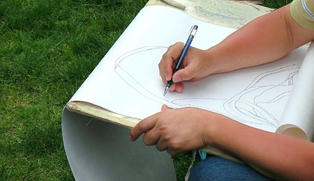 A draftsman is drawing a nature scene with a pencil