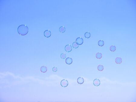 Soap bubbles are floating through the air against a blue summer skyの写真素材