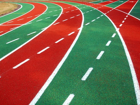 A running track in a stadium with markings in white, red and green and solid and broken linesの写真素材