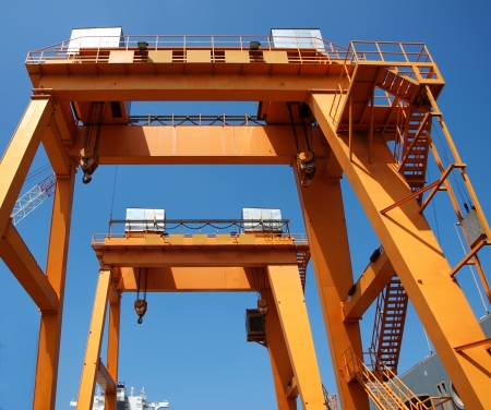 Two yellow overhead gantry cranes against a blue skyの写真素材