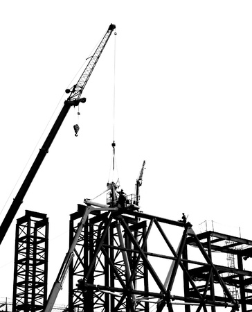 Steel construction with crane and workers in silhouetteの写真素材