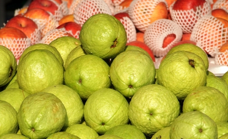 Fresh green guavas and apples for sale at an outdoor marketの写真素材