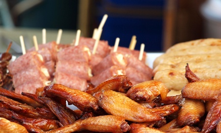 Barbecued chicken wings and ham skewers for sale at an outdoor stallの写真素材