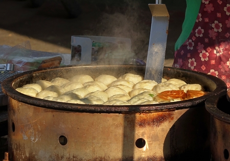 An outdoor vendor cooks Chinese buns stuffed with vegetables
の写真素材