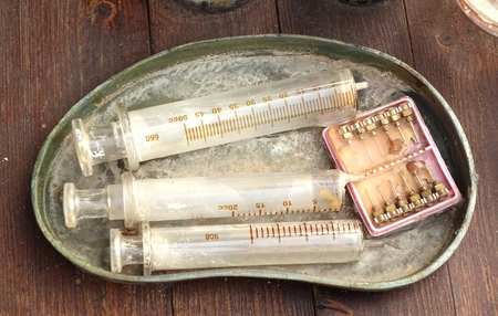 Old medical syringes and hypodermic needles in corroded trayの写真素材